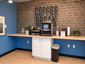 A coffee bar area with a coffee machine, a trash bin, and a sign that reads 'COFFEE BREAK love is brewing.'
