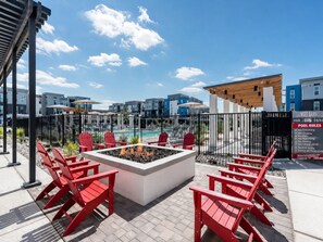 A rooftop pool area with red Adirondack chairs, a fire pit, and a poolside view of a residential complex. - Modern Jarrell Retreat, Near Austin, Pool+Parking (Jarrell)