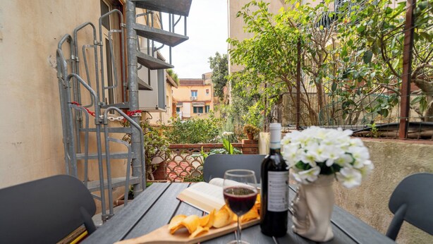 Un espace de restauration en plein air avec une table dressée pour deux personnes, agrémentée d’une bouteille de vin, d’un verre et d’une assiette de chips.