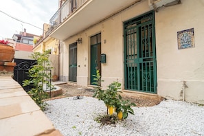 A building with a balcony, a door, and a window with green bars.