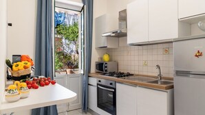 Une cuisine moderne avec des meubles blancs, une cuisinière à gaz, un four à micro-ondes et un réfrigérateur.