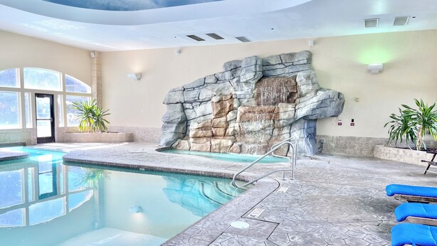 A swimming pool with a stone wall and blue lounge chairs. - 2071 | Upscale 2Q Suite Near Park City + Pool/Hot Tub (Midway)