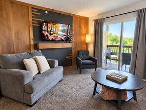 A living room with a sofa, armchair, and a round table with a board game.