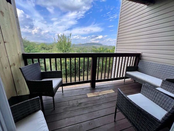 Eine Holzterrasse mit Korbmöbeln und einem Geländer mit Blick auf eine grüne Landschaft.