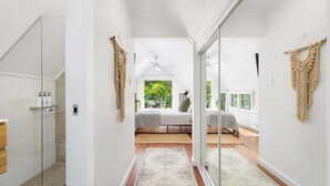 Une salle de bain moderne avec une douche à parois de verre, un meuble-lavabo en bois et un sol carrelé de blanc.