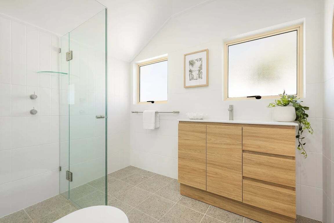 Une salle de bain moderne avec une douche à parois de verre, un meuble-lavabo en bois avec un miroir et une petite plante posée sur le meuble-lavabo.