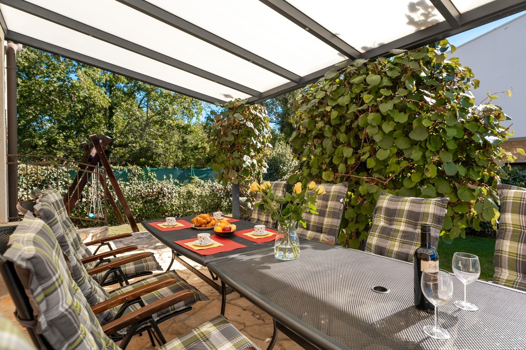 Un espace de restauration en plein air avec une table dressée pour deux personnes, entourée de sièges confortables.