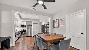 Une cuisine moderne équipée d’appareils électroménagers en acier inoxydable, une table à manger avec des chaises et un ventilateur de plafond.