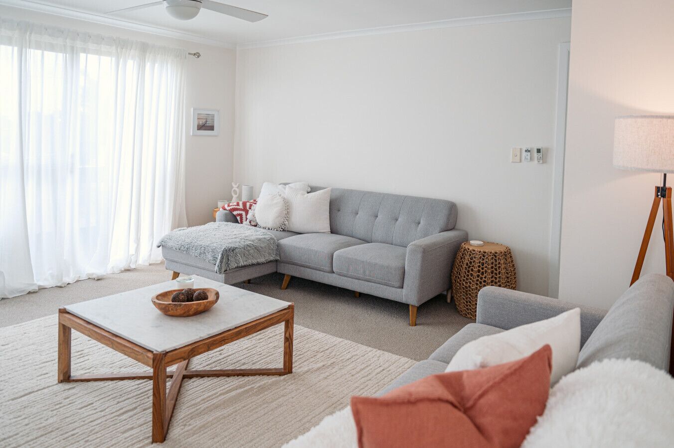A living room with a grey sofa, a wooden coffee table, and a side table with a lamp.