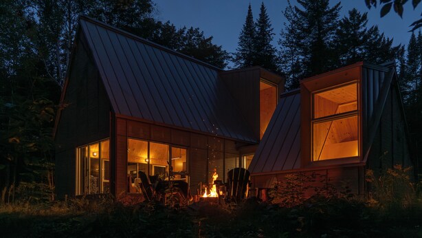 A modern house with a sloped roof, large windows, and a visible fire pit in the yard. - Chalet Saison | Nature • Sauna - Hiking - Softness (Chertsey)
