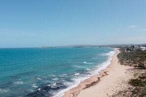 Une plage côtière avec un rivage sablonneux et des eaux d’un bleu limpide.