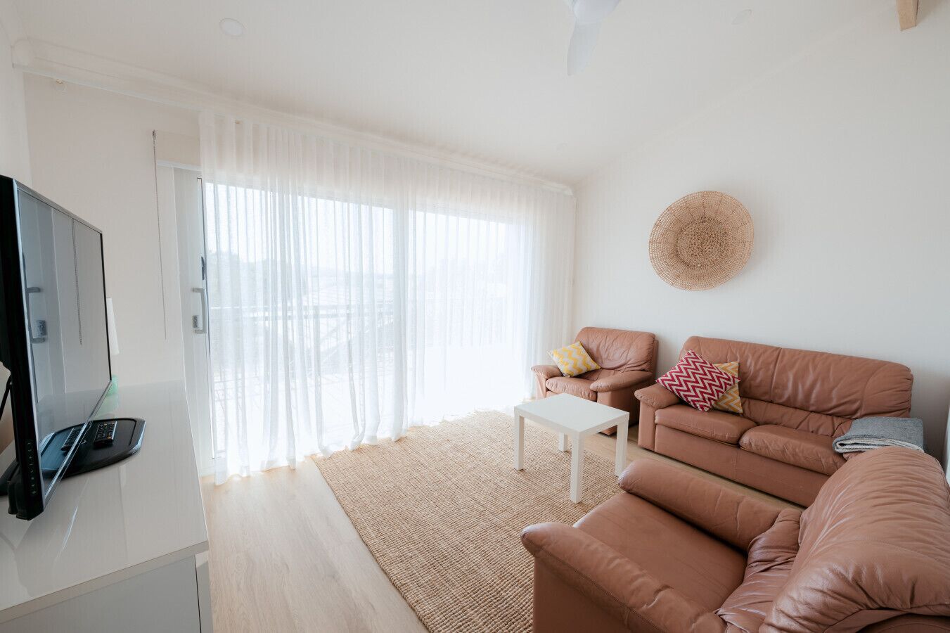 A modern living room with a sofa, a coffee table, and a TV on a stand.