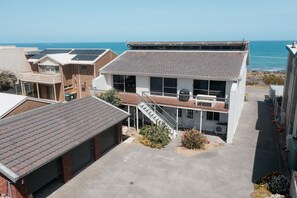 Une maison à deux étages avec un balcon, des panneaux solaires et une vue sur l’océan.