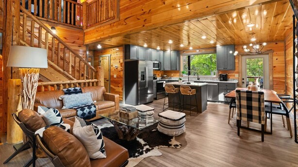 A spacious log cabin interior with a living area, kitchen, and dining space.