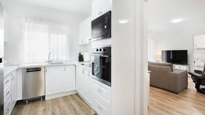 Een moderne keuken met witte kasten, een vaatwasser en een inbouwoven.