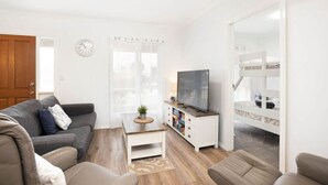 Een moderne woonkamer met een bank, een salontafel, een televisie en een stapelbed.