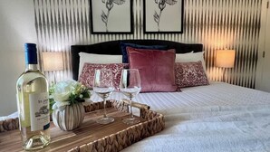A neatly made bed with a white comforter, a wooden tray with a bottle and glasses, and a vase of flowers. - Whispering Creek-Waterfront by Branson Landing (Branson)
