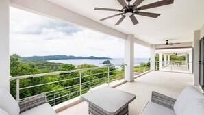 A balcony with a view of a lush landscape and the sea. - Flamingo Luxury Makai Villa Next to the Beach (Playa Flamingo)