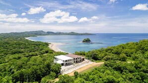 A coastal property with a large building, lush greenery, and a beach. - Flamingo Luxury Makai Villa Next to the Beach (Playa Flamingo)