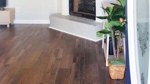 A living room with a fireplace, wooden flooring, a television, and a potted plant. - Dothan Westside Retreat (Dothan)