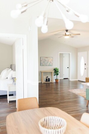 A spacious living room with a wooden floor, a dining area with a table and chairs, a ceiling fan, and a large window. - Dothan Westside Retreat (Dothan)