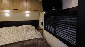 A compact bedroom with a bed, a TV, and a window with blinds. - New 2026 RV / Mountain View / ATVs (Lincoln)