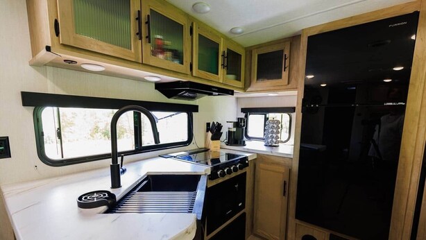 A compact RV kitchen with a sink, stove, and black refrigerator. - New 2026 RV / Mountain View / ATVs (Lincoln)