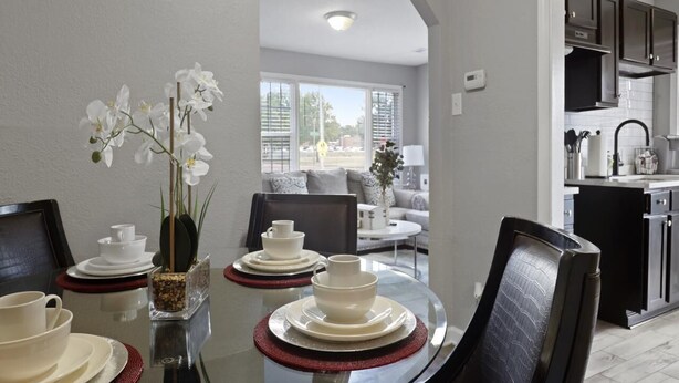 A modern dining area with a glass table, white plates, and black chairs. - Stylish Memphis Home w/ Large Yard + Cozy Interior (Memphis)