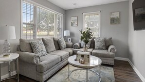 A living room with a grey sofa set, a round coffee table, and a small side table. - Stylish Memphis Home w/ Large Yard + Cozy Interior (Memphis)