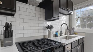 A modern kitchen with a gas stove, stainless steel appliances, white subway tiles backsplash, and black cabinets. - Stylish Memphis Home w/ Large Yard + Cozy Interior (Memphis)