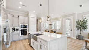 A modern kitchen with white cabinetry, stainless steel appliances, and a large island. - New 30A Listing! Remodeled Home + New Golf Cart (Inlet Beach)