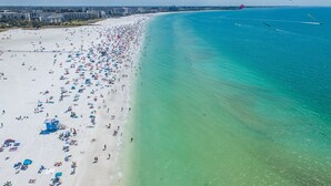 Una playa con numerosas sombrillas y gente, una torre de salvavidas y una vista despejada del océano.