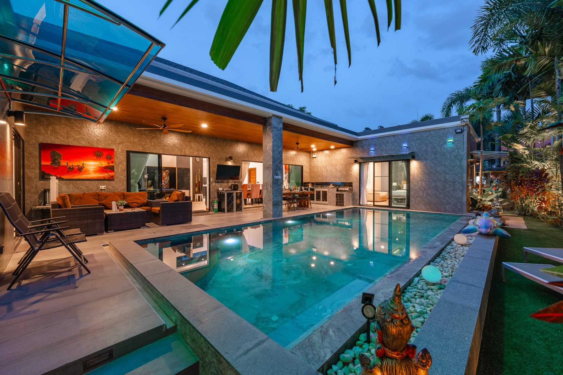 A modern house with a swimming pool, outdoor seating, and a large TV screen.