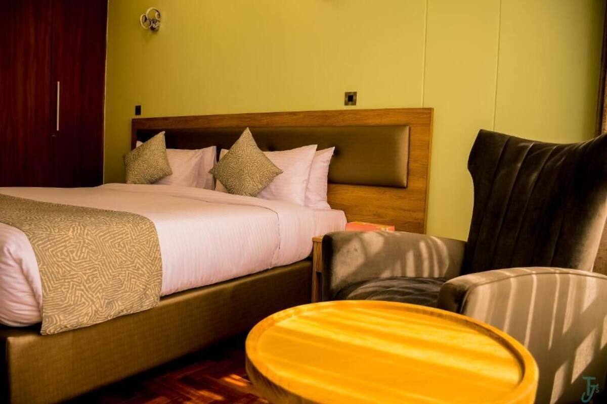 A hotel room with a bed, a chair, and a small round table.