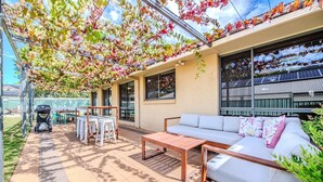 An outdoor patio area with a sofa, table, chairs, and a barbecue grill. - Under the Grapevines with Pool & BBQ (Dubbo)