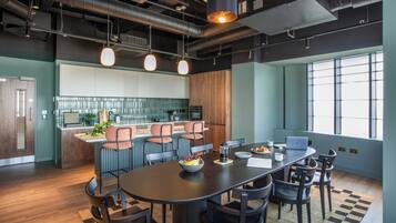 A modern kitchen with a central island, bar seating, and a dining area with a large table and chairs.