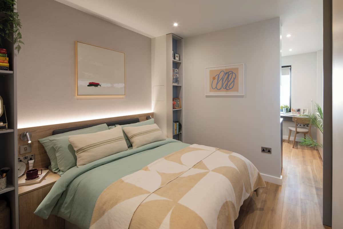 A modern bedroom with a bed, bedside tables, a desk, and a bookshelf.