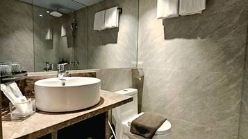 A modern bathroom with a large mirror, a round sink, a toilet, and a shower.