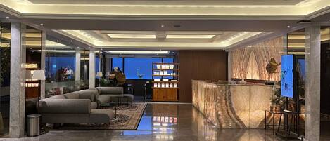 A spacious lobby with a reception desk, seating area, and a view into the hotel rooms.