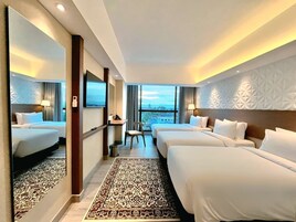 Une chambre d’hôtel avec deux lits, un grand miroir, une vue sur la ville et un tapis à motifs.