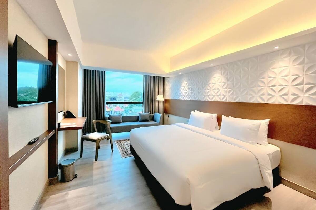Een hotelkamer met een groot bed, een bureau, een stoel en een televisie.