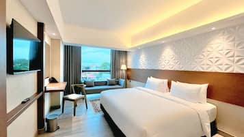 A hotel room with a large bed, a desk, a chair, and a TV.