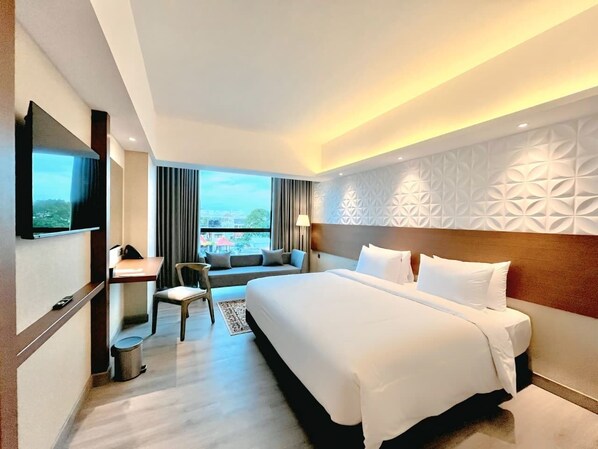 A hotel room with a large bed, a desk, a chair, and a TV. - The Jogja Hotel & Conference Center - Malioboro (Yogyakarta)