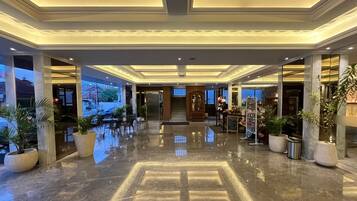 Un hall de hotel con suelo de mármol pulido, un mostrador de recepción y vistas al exterior.