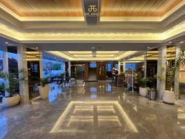 Un hall d’hôtel doté d’un sol en marbre poli, d’un comptoir de réception et offrant une vue sur l’extérieur.