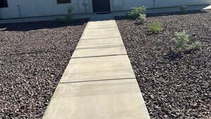 Ein Haus mit einem Betonweg, der zu einer schwarzen Tür führt, umgeben von Kies.