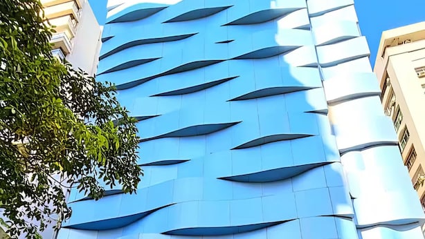 A hotel with a modern facade featuring a blue and white color scheme and a distinctive wave-like pattern. - Modern Flat in Gonzaga, just a block from the beach. (Santos)
