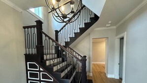 A staircase with a black railing and white trim, leading to a room with wooden flooring and a door.