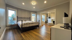 A bedroom with a bed, bedside tables, a walk-in closet, and a bathroom.