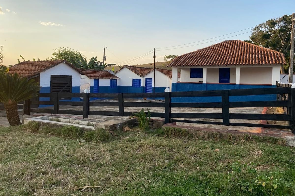 A row of white buildings with blue trim and tiled roofs, surrounded by a black fence.